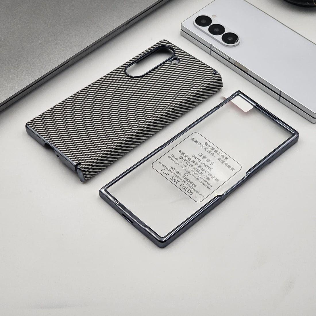 Two phone cases, one with a carbon fiber texture and the other clear with text, on a light gray surface.